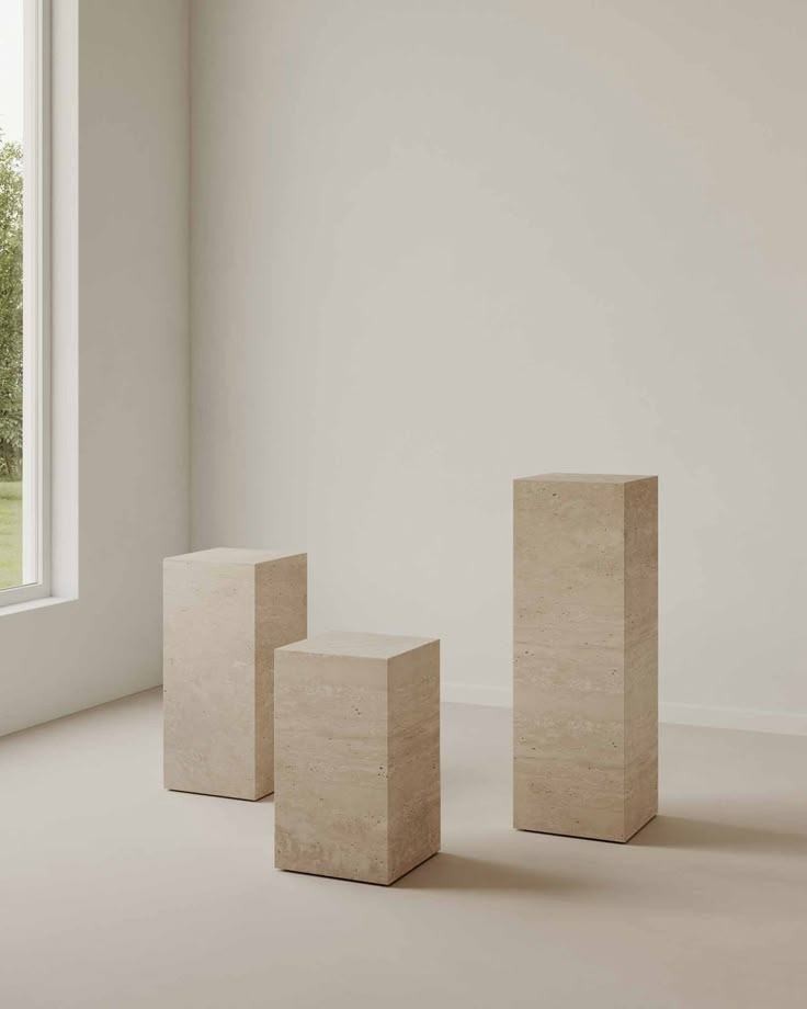 Tres pedestales de piedra clara en una sala blanca