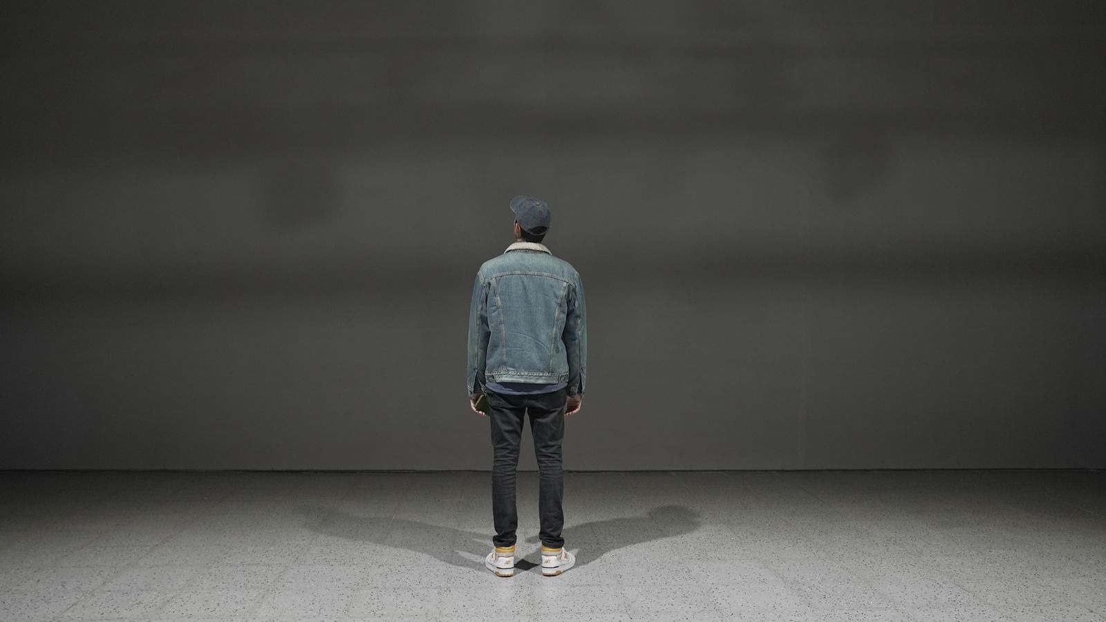 La sala vacía: pared y piso grises, y una persona de espaldas